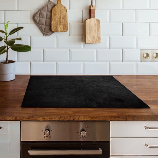 Zwarte inductiebeschermer met houtnerfstructuur op een houten aanrecht.