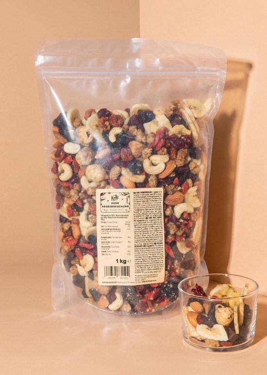 Een doorzichtige zak gevuld met een mix van noten en fruit, met daarnaast een glas gevuld met de mix.