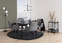 Interieur met een ronde, zwarte eettafel, vier grijze eetkamerstoelen met armleuningen en een zwarte vloerlamp.