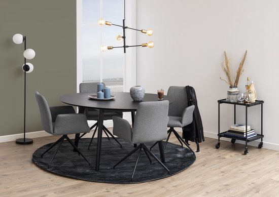 Interieur met een ronde, zwarte eettafel, vier grijze eetkamerstoelen met armleuningen en een zwarte vloerlamp.