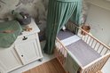 Babykamer met wieg, commode, speelgoed en groene textielproducten.