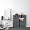 Dressoir met 9 grijze lades, houten top en zwart frame, in een slaapkamer.
