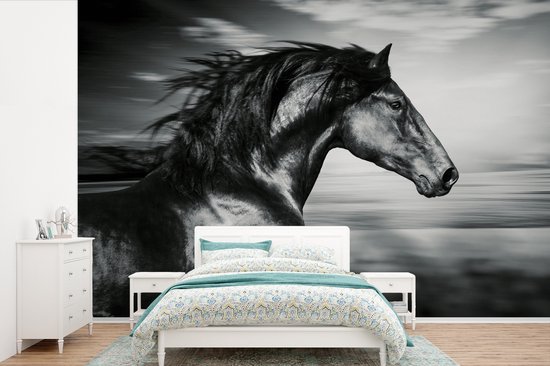 Zwart-wit paardenbehang in een slaapkamer met een wit bed en kleurrijk beddengoed.