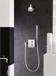 Douche met zwarte mozaïekwanden, chroomkleurige handdouche, douchekop en thermostaatkraan.