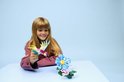 Une fille regarde un colibri LEGO et une fleur bleue.