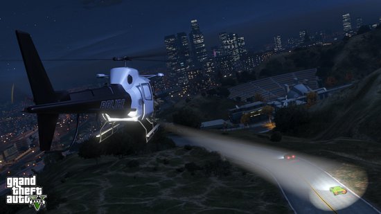 Een politiehelikopter vliegt 's nachts over een stad, met een zoeklicht gericht op de weg.