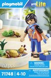 Playmobil jongen met schildpaddenterrarium. Jongen draagt een oranje vest met een kleurrijk patroon over een zwart shirt.