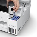 Een hand vult een Epson inktfles bij in de cyaan-, magenta- en gele inktinktcontainers van een witte printer.