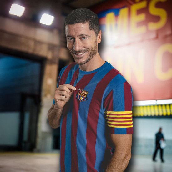 Man met een retro FC Barcelona shirt, blauwe en rode strepen, toont embleem.