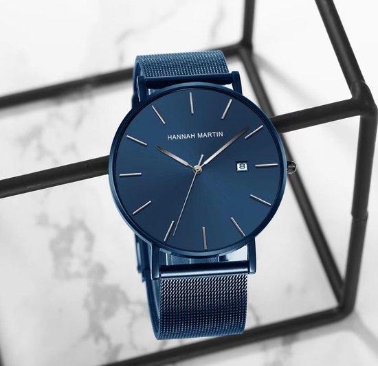 Hannah Martin horloge met blauwe wijzerplaat en mesh band, in abstracte zwarte houder.