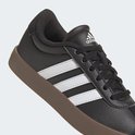 Close-up van zwarte adidas sneaker met witte strepen en bruine zool.