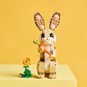 Lapin LEGO avec carotte et fleur, sur table jaune.