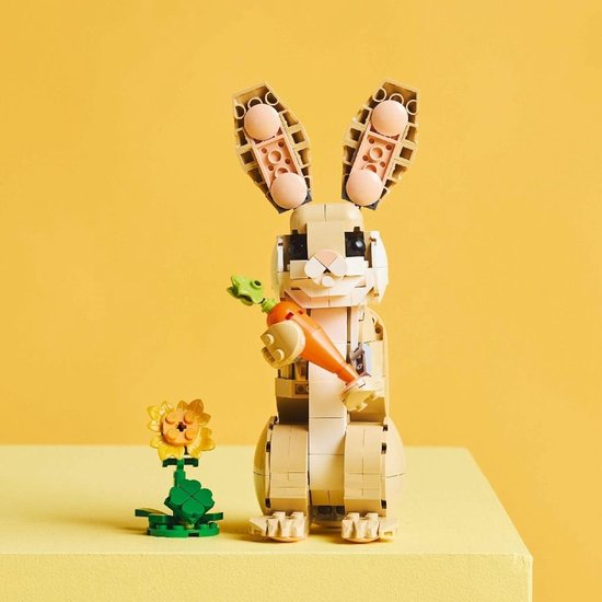Lapin LEGO avec carotte et fleur, sur table jaune.