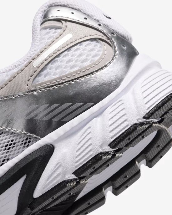 Close-up van de zijkant van een witte Nike sneaker met zilveren en grijze details.