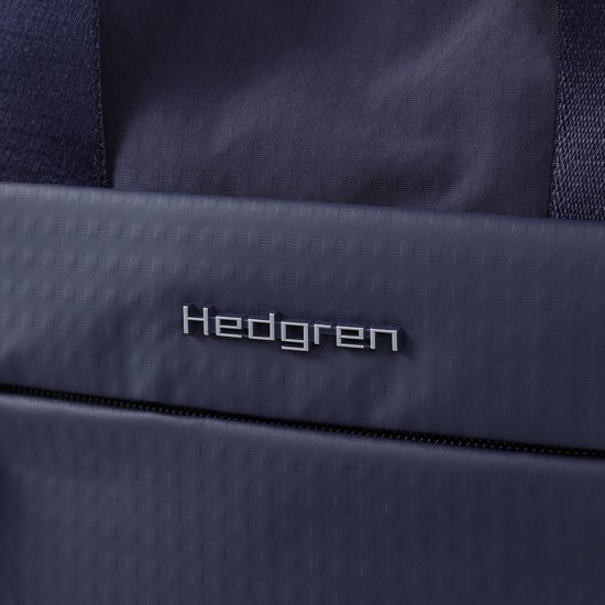 Detail van het zilverkleurige Hedgren logo op een donkerblauwe tas met textuur.