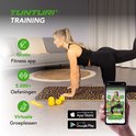 Vrouw doet oefening op panterprint fitnessmat. Mobiele telefoon toont Tunturi app met 5000+ oefeningen.