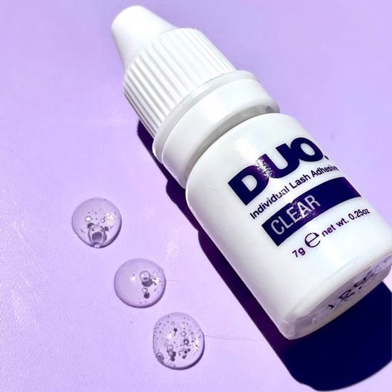Flesje DUO Individual Lash Adhesive Clear met druppels transparante lijm op een paarse achtergrond.