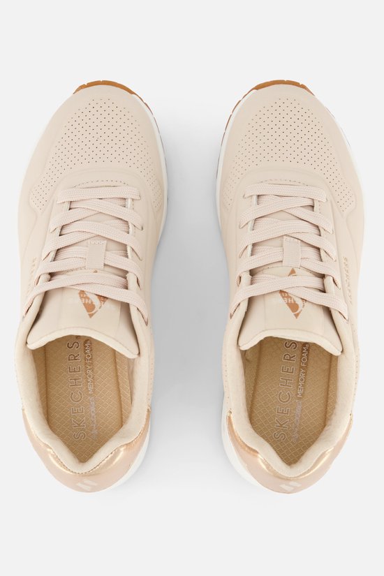 Deux baskets Skechers UNO naturelles vues de dessus. Avec lacets, accent doré au talon et semelles blanches.