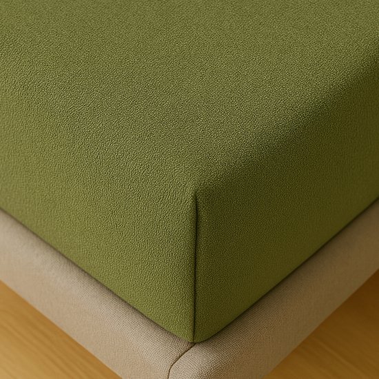 Groen hoeslaken met een subtiele textuur, zichtbaar op de hoek van een matras.