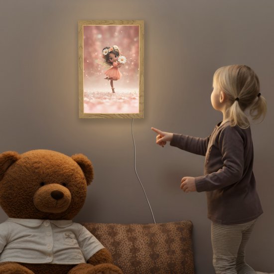 Meisje wijst naar een oplichtende lamp met een fee op de muur in een kinderkamer, naast een teddybeer.
