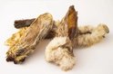 Een stapel gedroogde konijnenoren voor honden, met bruine en witte vachtresten.