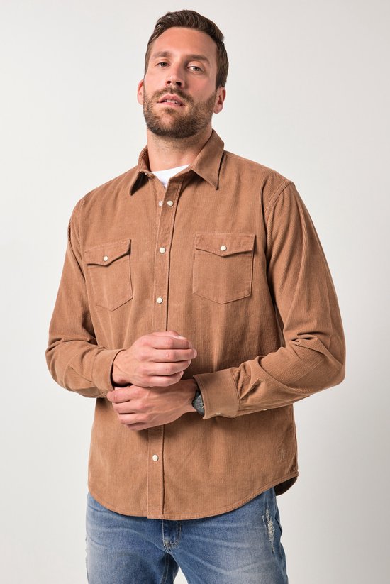 Model draagt een bruin corduroy overhemd met lange mouwen, twee borstzakken en een wit shirt eronder.