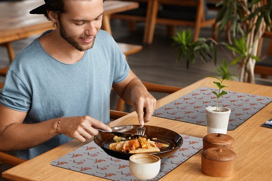 Homme à table avec une nappe à motifs flamants roses.