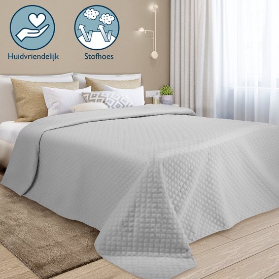 Lichtgrijze sprei met ruitpatroon op een bed. Huidvriendelijk en stofvrij.