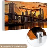 MuchoWow® Glasschilderij 160x80 cm - Schilderij acrylglas - De Brooklyn Bridge bij een oranje hemel - Foto op glas - Schilderijen