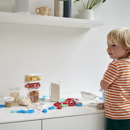 Garçon dans la cuisine près de boîtes de rangement Mepal Modula remplies de bonbons et de pâtes.