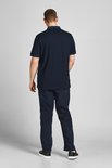 Achterkant van een donkerblauw poloshirt, gedragen door een man met donkere spijkerbroek.