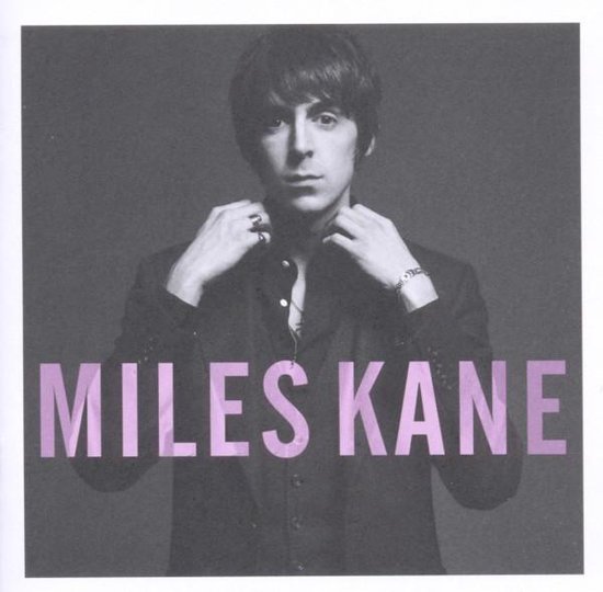 Man met donker haar, draagt een zwart pak. Tekst 'MILES KANE' in paars op de voorgrond.