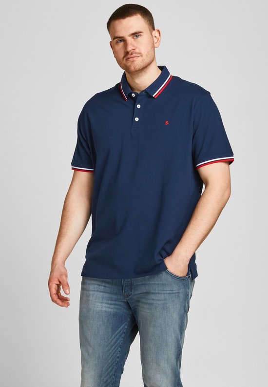 Donkerblauwe polo met rode en witte strepen op kraag en mouwen. Een man draagt de polo.