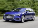 Blauwe Audi A6 C8 Avant rijdt op een weg door een bosrijke omgeving.