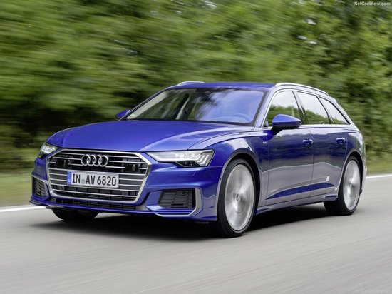 Blauwe Audi A6 C8 Avant rijdt op een weg door een bosrijke omgeving.