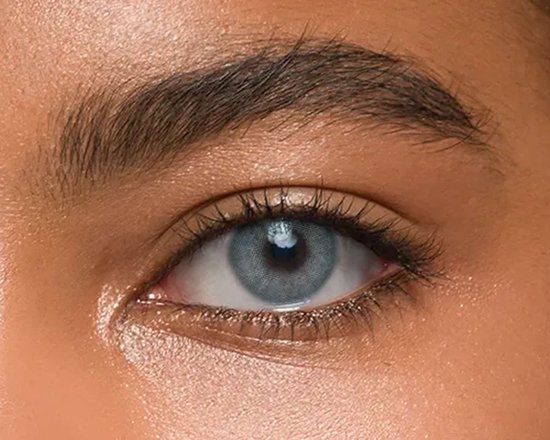 Een close-up van een gebruinde huid met een blauwgrijs gekleurd oog. Het oog is opgemaakt.