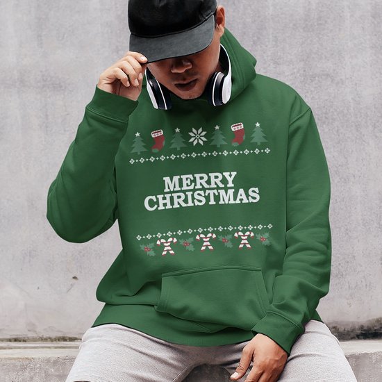 Persoon met zwarte pet en koptelefoon draagt een groene hoodie met Merry Christmas-print en kerstmotieven.