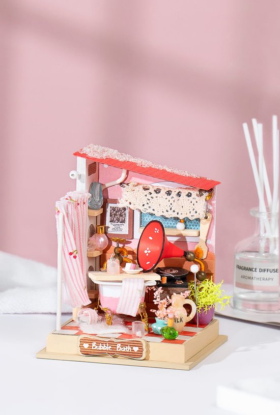 Miniatuur badkamer met rood dak, badkuip, grammofoon en planten, naast een geurverspreider.