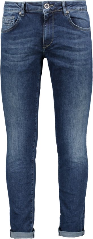 Model draagt donkerblauwe, slim-fit spijkerbroek met opgerolde zoom.
