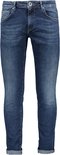 Model draagt donkerblauwe, slim-fit spijkerbroek met opgerolde zoom.