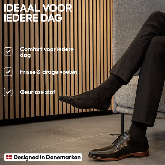 Man in een stoel met zwarte sokken van merinowol, die comfort en frisse voeten beloven.