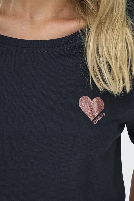 Close-up van een donkerblauw T-shirt met een roze glitter hartje en 'ONLY' erop.