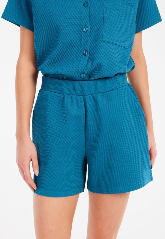 Turquoise dames short met elastische tailleband, steekzakken en een subtiel textuurpatroon.