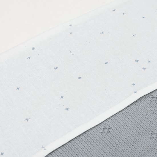 Lichtblauwe wiegdeken met een patroon van kleine blauwe sterretjes en kruisjes op een witte ondergrond.