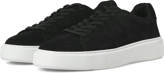Zwarte suède sneakers met witte zolen, schuin van voren gefotografeerd.
