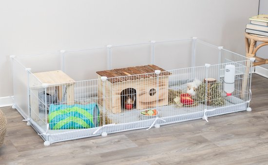 Witte metalen ren met speelhuisje, dieren en accessoires, staand op een houten vloer.