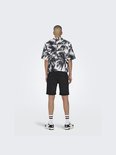 Man met palmbomenprint shirt en zwarte shorts, gezien van achteren.