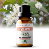 Bruine glazen fles etherische tea tree olie met zwart dopje. Label met "Etherische olie Tea Tree" en "100% Biologische olie". Achtergrond met witte bloesem.