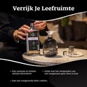 Vrouw vult een geurbrander met Belle Vie geurolie uit een fles met trechter.