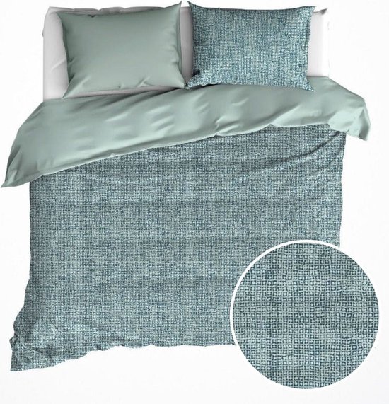 Housse de couette verte avec motif géométrique gris et linge de lit vert uni. Gros plan sur le motif.